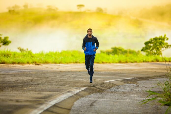 Photo by Tikkho Maciel man in track suit jogging on concrete road
