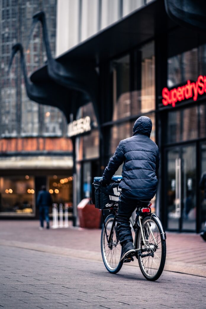 Photo by Michael Fousert man in black leather jacket riding on bicycle during daytime
