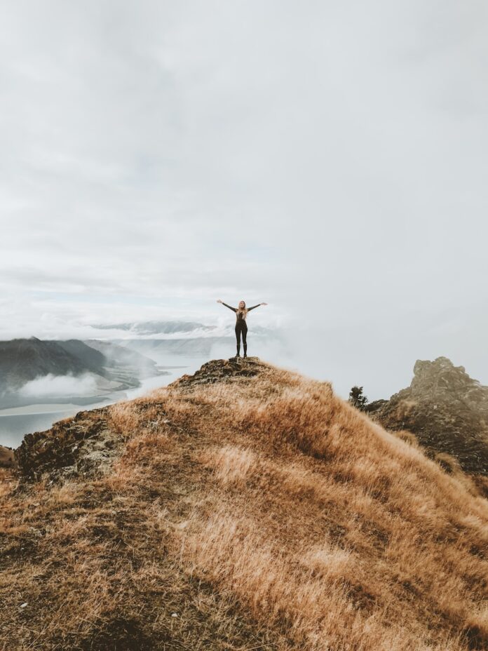 Photo by Samuel Scrimshaw woman standing on top of hill