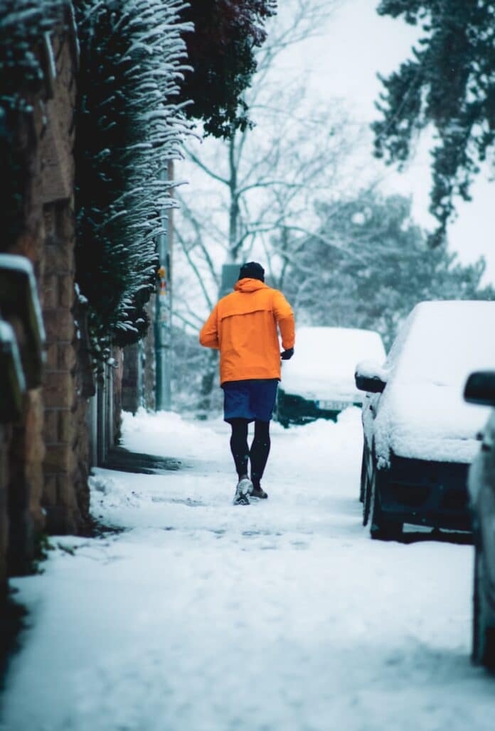 Photo by Christian Lue person in orange hoodie walking on snow covered pathway during daytime