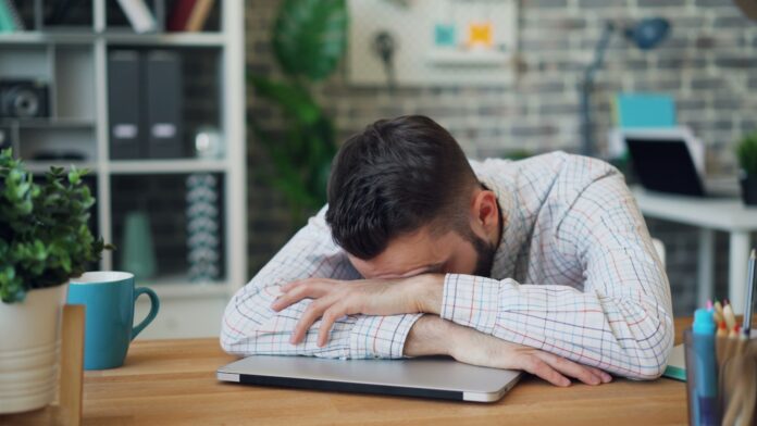 Photo by Vitaly Gariev a man sitting at a desk with his head in his hands