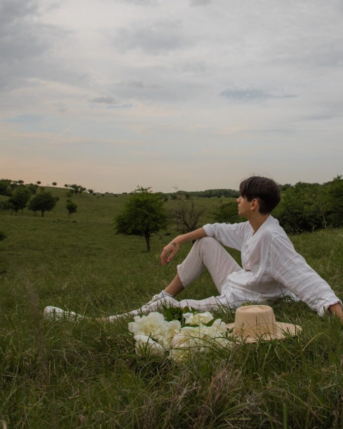 Photo by Jovan Vasiljević a man sitting on a blanket in the middle of a field
