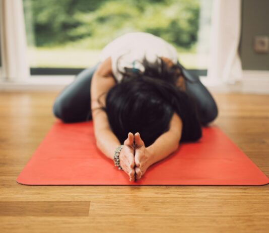 목·어깨 힐링: 승모근 보톡스 대신 선택하는 5분의 이완 woman in white shirt lying on red mat on brown wooden table