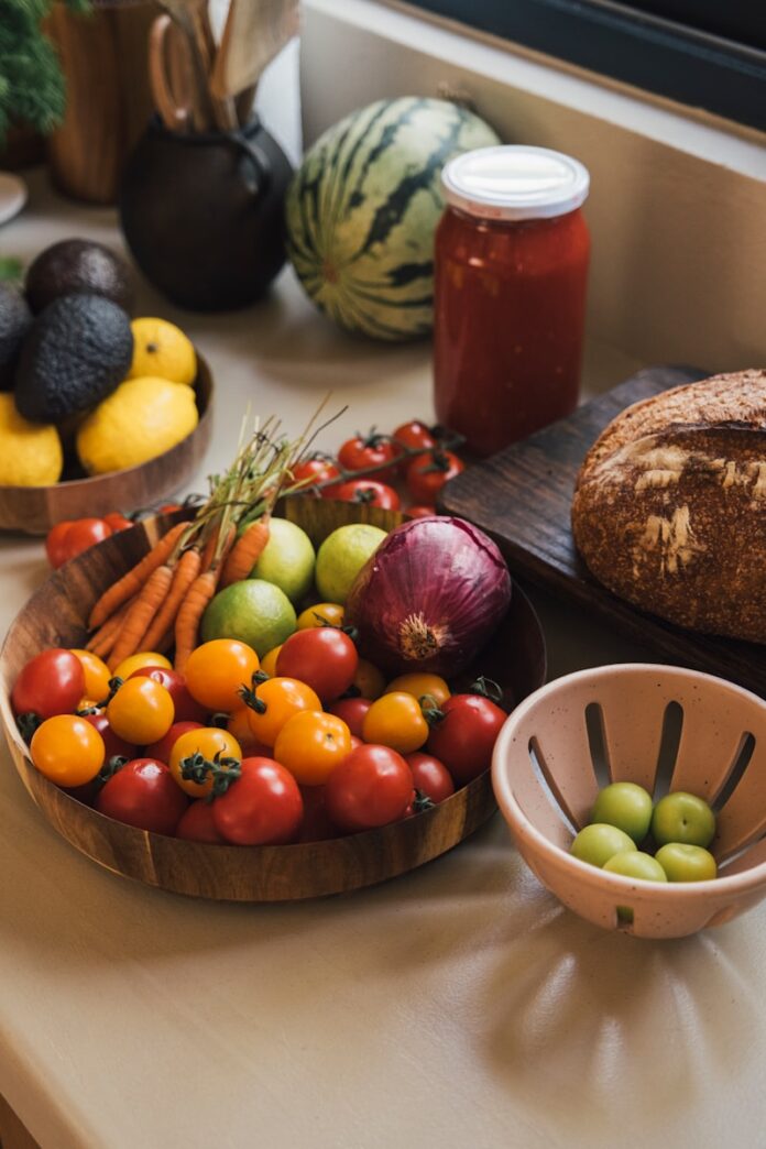 Fresh produce including tomatoes, carrots, and avocados on a counter.