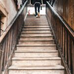 “근육 관리도 일상 속 작은 루틴에서부터”… 건강 트렌드로 떠오른 ‘생활 근력 챙기기’ A person walks up a wooden staircase.