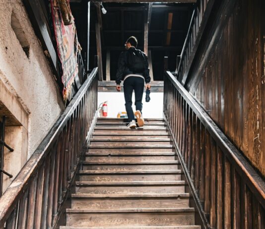 “근육 관리도 일상 속 작은 루틴에서부터”… 건강 트렌드로 떠오른 ‘생활 근력 챙기기’ A person walks up a wooden staircase.